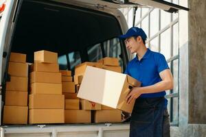 Smiling delivery man standing in front of his van with Holding Box and tablet delivery home and shipping photo