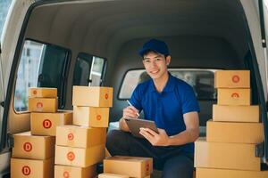 Smiling delivery man standing in front of his van with Holding Box and tablet delivery home and shipping photo