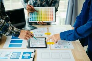 UX developer and ui designer brainstorming about mobile app interface wireframe design with customer breif and color code at modern office. photo