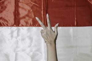 Hands gesturing signs of number isolated by Indonesian red and white flag. Indonesia's independence day concept photo