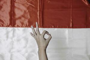 Hands gesturing OK sign by fingers isolated by Indonesian red and white flag. Indonesia's independence day concept photo