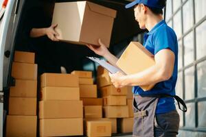 Smiling delivery man standing in front of his van with Holding Box and tablet delivery home and shipping photo