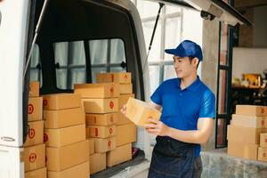 Smiling delivery man standing in front of his van with Holding Box and tablet delivery home and shipping photo