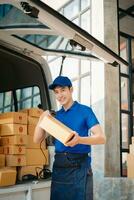 Smiling delivery man standing in front of his van with Holding Box and tablet delivery home and shipping photo