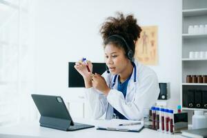 female doctor sitting on work desk Medical online, e health concept. Doctor using laptop for work, video call video chat with colleagues. photo