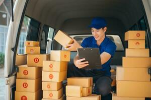 Smiling delivery man standing in front of his van with Holding Box and tablet delivery home and shipping photo