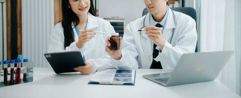 Medical team having a meeting with doctors in white lab coats and surgical scrubs seated at a table discussing a patients working online using computers in the medical industry photo