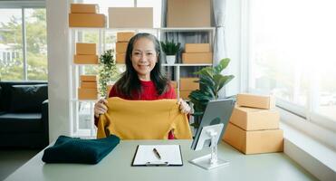 Mature business owner woman prepare parcel box and standing check online orders for deliver to customer on tablet, laptop Shopping Online photo