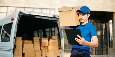 Smiling delivery man standing in front of his van with Holding Box and tablet delivery home and shipping photo