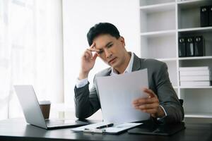 Asian business man is stressed, bored, and overthinking from working on a tablet at the modern office. photo