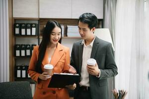 Happy two Asian business woman holding coffee cup in coworking office photo