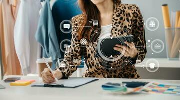 Woman hand using a laptop, smartphone and tablet and writing notebook at the office of her business online shopping. In home with vr icon photo