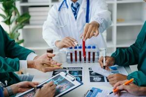Medical team having a meeting with doctors in white lab coats and surgical scrubs seated at a table discussing a patients working online using computers in the medical industry photo