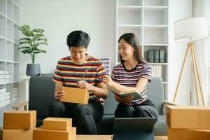 joven asiático hombre y mujer a oficina de su negocio en línea compras.in hogar oficina foto