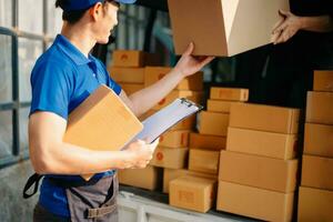 Smiling delivery man standing in front of his van with Holding Box and tablet delivery home and shipping photo