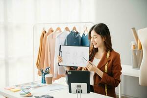 Diverse female fashion designers at work with tailor centimeters on necks and holds tablet and smartphone. independent creative design photo