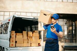 Smiling delivery man standing in front of his van with Holding Box and tablet delivery home and shipping photo