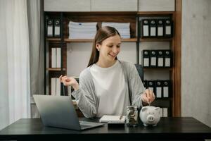 caucásico mujer son poniendo monedas en un cerdito banco para un negocio ese crece para lucro y ahorro dinero para el futuro. foto