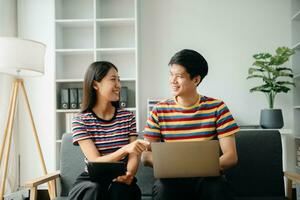 Two asian students learning together online with a laptop, tablet and tutor together in living room at home. photo