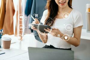 mujer mano utilizando un computadora portátil, teléfono inteligente y tableta y escritura cuaderno a el oficina de su negocio en línea compras. en hogar con vr icono foto