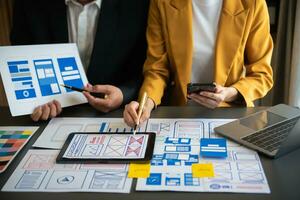UX developer and ui designer brainstorming about mobile app interface wireframe design with customer breif and color code at office. photo