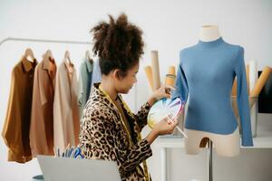 Diverse female fashion designers at work with tailor centimeters on necks and holds tablet and smartphone. independent creative design photo