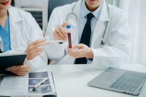 Medical team having a meeting with doctors in white lab coats and surgical scrubs seated at a table discussing a patients working online using computers in the medical industry photo