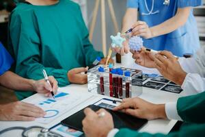 Medical team having a meeting with doctors in white lab coats and surgical scrubs seated at a table discussing a patients working online using computers in the medical industry photo