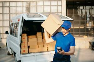 Smiling delivery man standing in front of his van with Holding Box and tablet delivery home and shipping photo