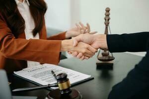 Woman lawyer hand and women client shaking hand collaborate on working agreements with contract documents at the modern office. photo