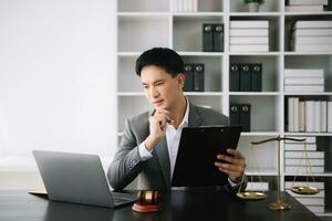 Attractive young lawyer in office Business man and lawyers discussing contract papers laptop and tablet with brass scale on  desk in office. photo