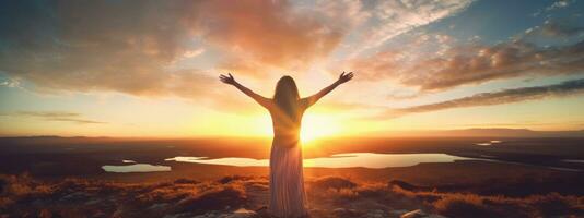 Woman standing on top of the mountain with arms outstretched against the mountain scenery photo