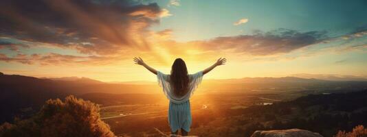 Woman standing on top of the mountain with arms outstretched against the mountain scenery photo