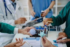 Medical team having a meeting with doctors in white lab coats and surgical scrubs seated at a table discussing a patients working online using computers in the medical industry photo