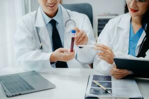 Medical team having a meeting with doctors in white lab coats and surgical scrubs seated at a table discussing a patients working online using computers in the medical industry photo
