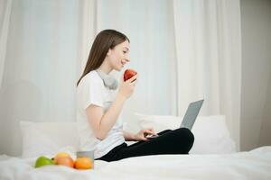 Beautiful young woman on a white bed with coffee cub and using smart phone at home. lifestyle concept photo