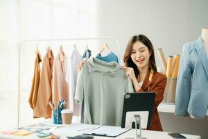 Fashion blogger concept, Young Asian women selling clothes on video streaming.Startup small business SME, using smartphone or tablet taking receive photo