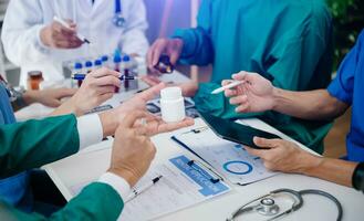 Medical team having a meeting with doctors in white lab coats and surgical scrubs seated at a table discussing a patients working online using computers in the medical industry photo