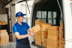 Smiling delivery man standing in front of his van with Holding Box and tablet delivery home and shipping photo