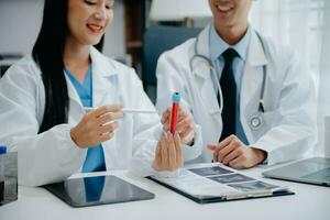 Medical team having a meeting with doctors in white lab coats and surgical scrubs seated at a table discussing a patients working online using computers in the medical industry photo