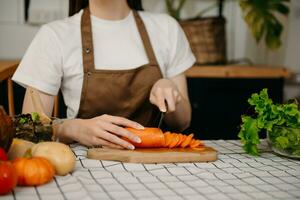 Young Woman cooking dinner has video call conversation in kitchen. Smiling happy female talking with friend using application on computer. photo