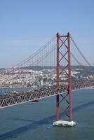 Lisbon, Portugal - May 10, 2023 - The Ponte 25 de Abril bridge in Lisbon, Portugal, with the cityscape in the background photo