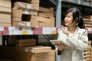 business woman using digital tablet checking amount of stock product inventory on shelf at distribution warehouse factory.logistic business shipping and delivery. photo