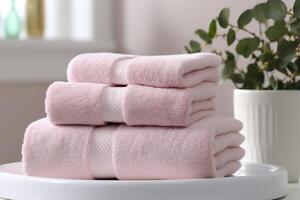 the world's softest towels against a minimalistic background. Stacked white towels sit on top of a soap dish in a bathroom. photo
