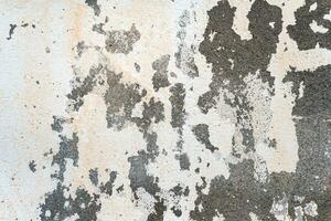 Peeled and cracked white paint on an old concrete wall. Abstract textured background. photo