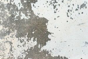 Peeled white paint on an old rough concrete wall. Abstract textured background. photo