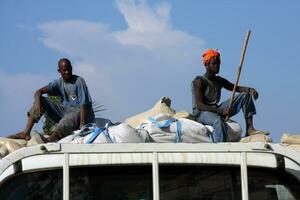 Luanda, Angola, Africa February 12 2009   Two men riding on top of a truck to protect a shipment of grain going to the market photo