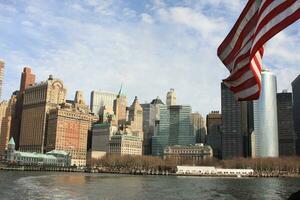 Skyline of New York City with the American Flag waving in the foreground photo