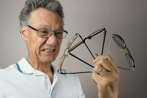 Mature Man checking out and holding up all his old prescription glasses photo