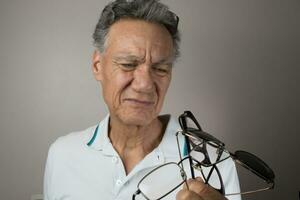 Mature Man checking out and holding up all his old prescription glasses photo